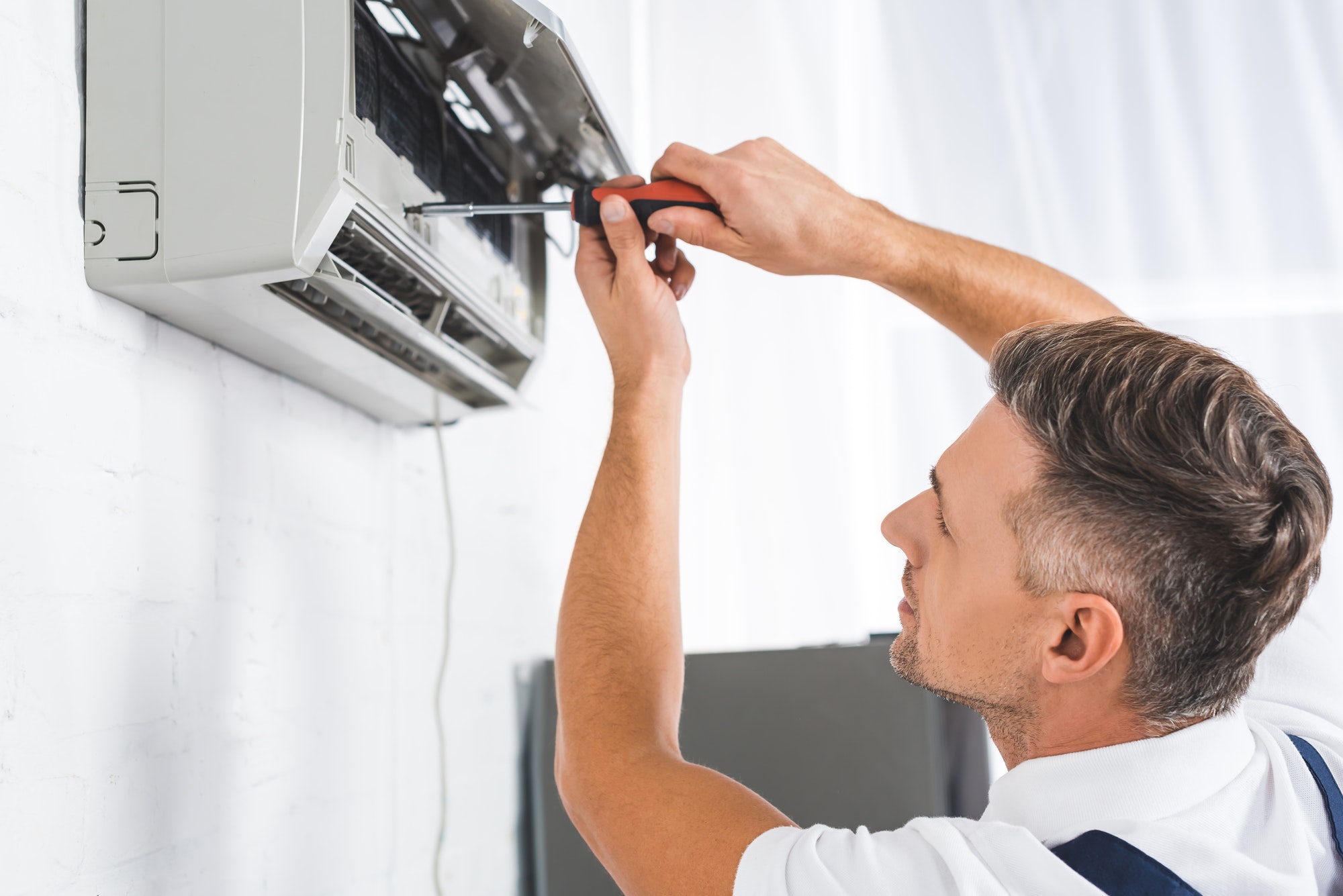 handsome-adult-man-repairing-air-conditioner-with-screwdriver.jpg